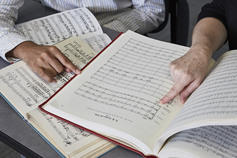 Two hands are pointing at an open book of sheet music
